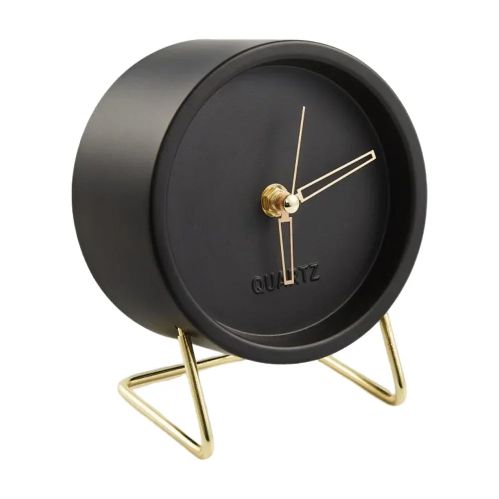 Black round desk clock with gold-coloured hands and an angular wire stand on a white background