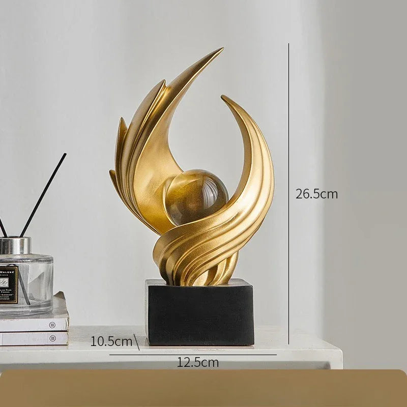 Gold-coloured abstract sculpture shown with 26.5 cm height, 12.5 cm width and 10.5 cm depth measurements.