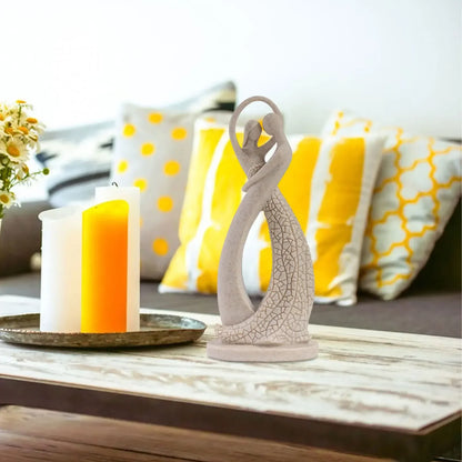Beige abstract dancing couple sculpture on a coffee table beside yellow candles and a sofa with yellow cushions
