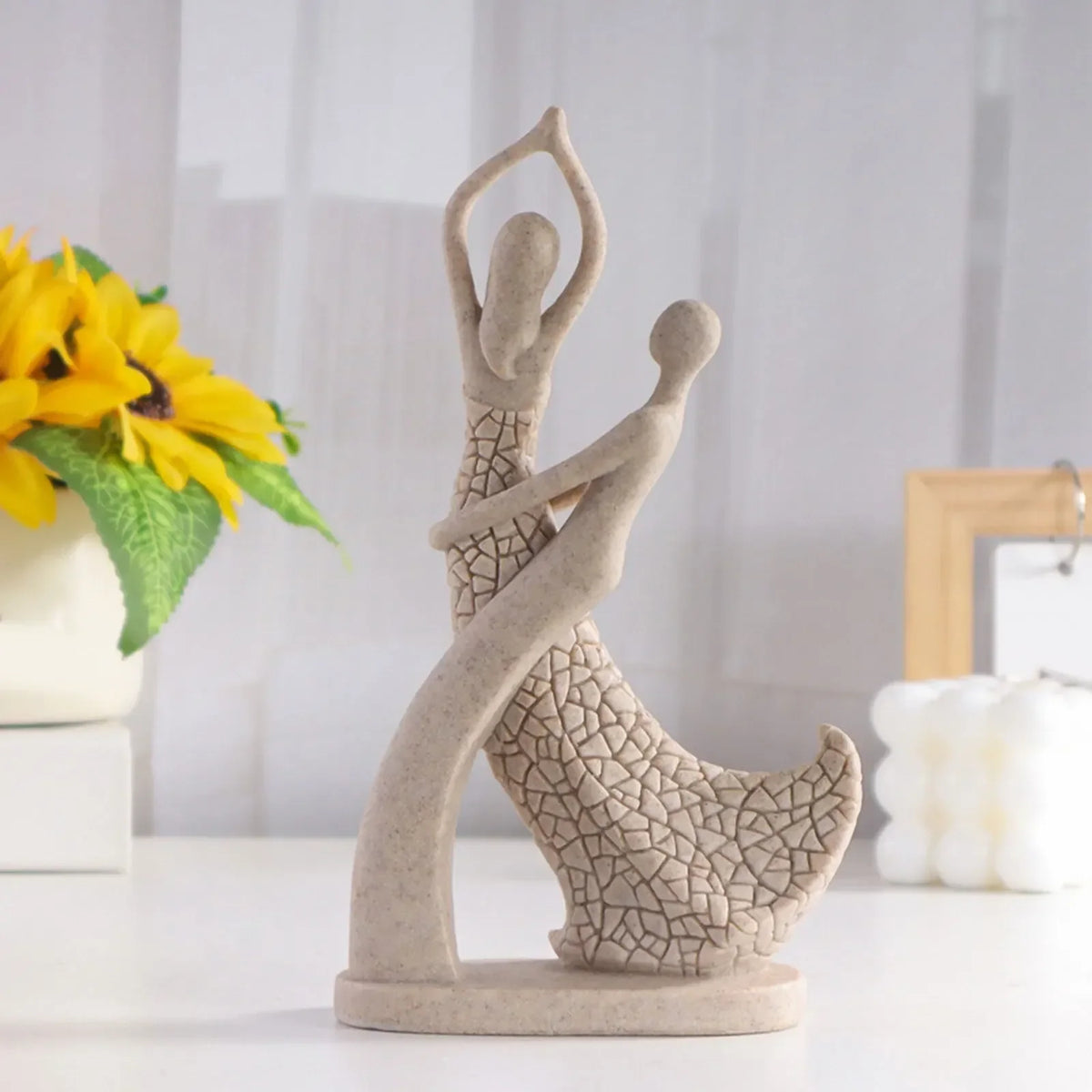 Beige abstract couple sculpture with one figure leaning back and the other raising both arms above its head
