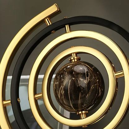 Close-up of the abstract globe sculpture's black and gold-coloured rings around a dark marbled sphere.