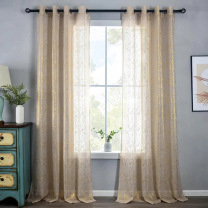 Beige sheer curtains with gold-coloured speckles hanging from a black rod around a bright window.