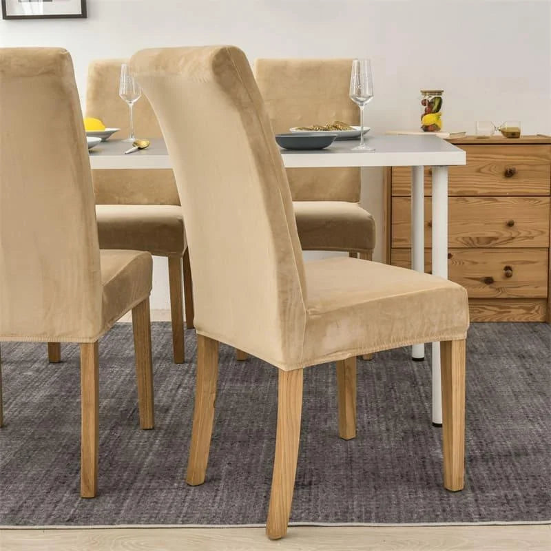 Rear view of a dining chair fitted with a beige suede cover, showing the backrest and exposed wooden legs.