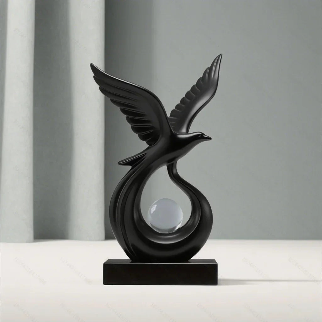 Front view of a black bird sculpture with raised wings and a clear sphere on a black base.