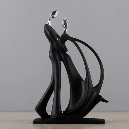 Black abstract dancing couple sculpture with silver-coloured heads and a long curved skirt on a rectangular base