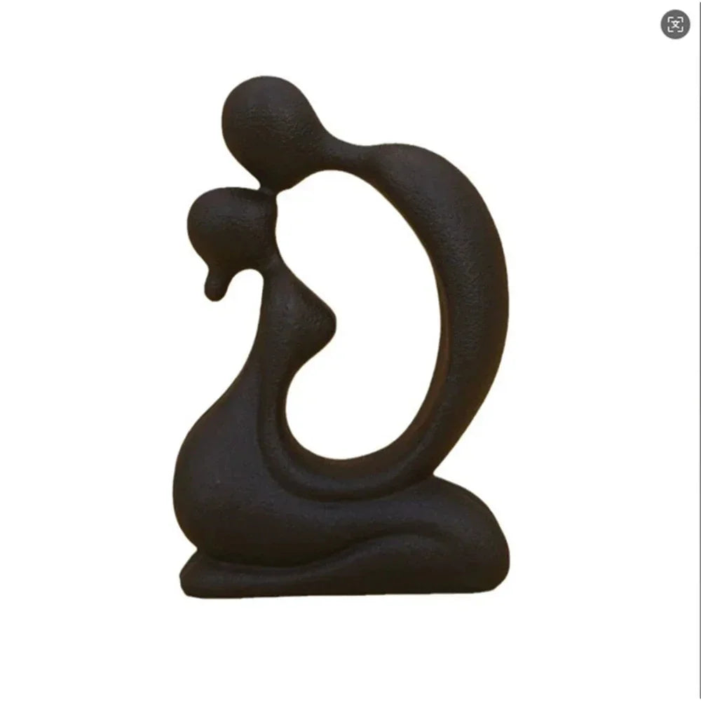 Black abstract kissing couple sculpture with an open oval centre shown on a white background