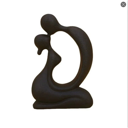 Black abstract kissing couple sculpture with an open oval centre shown on a white background
