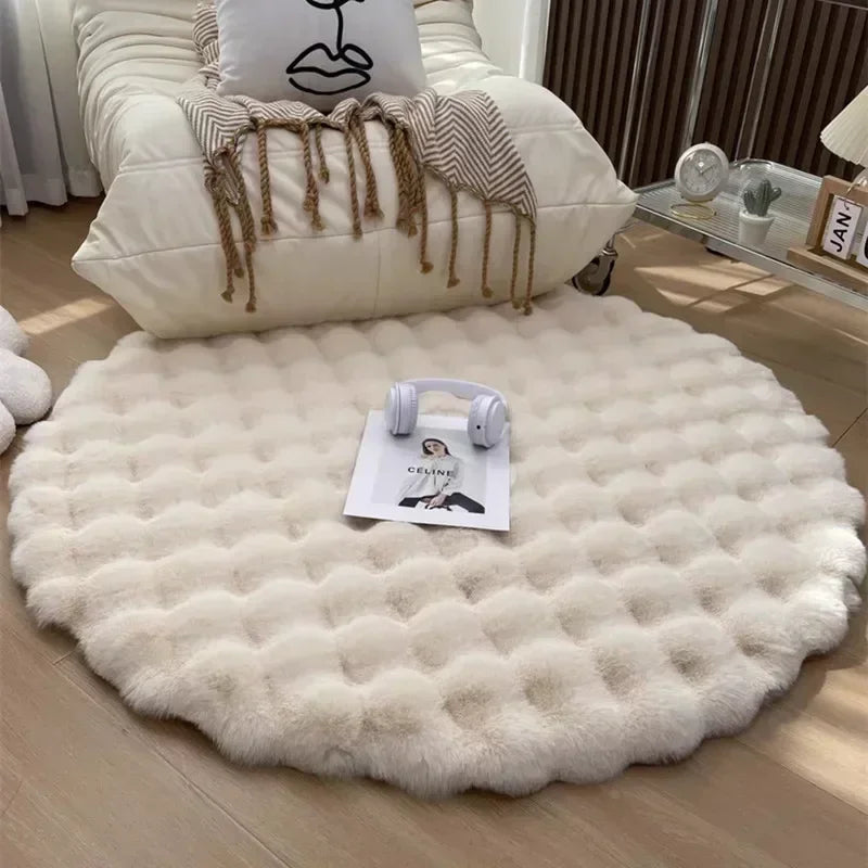 Round cream plush rug with a raised grid pattern in front of an armchair, with headphones and a magazine