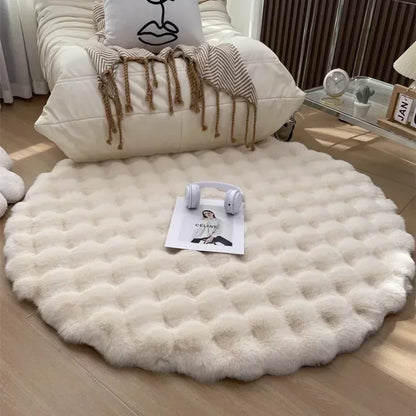 Round cream plush rug with a raised grid pattern in front of an armchair, with headphones and a magazine