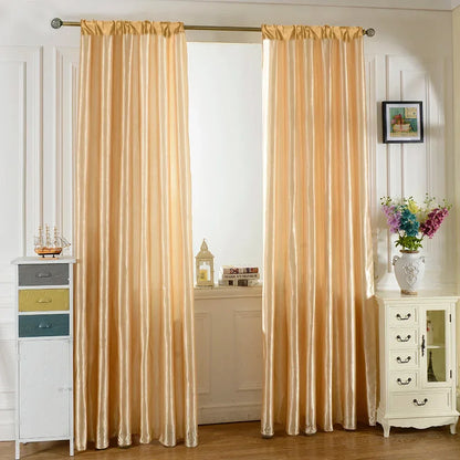 Cream satin-finish rod-pocket curtains framing a bright window beside a chest of drawers.