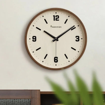 Cream-dial wall clock with a brown rim and black hands above a cabinet, with foliage in the foreground.