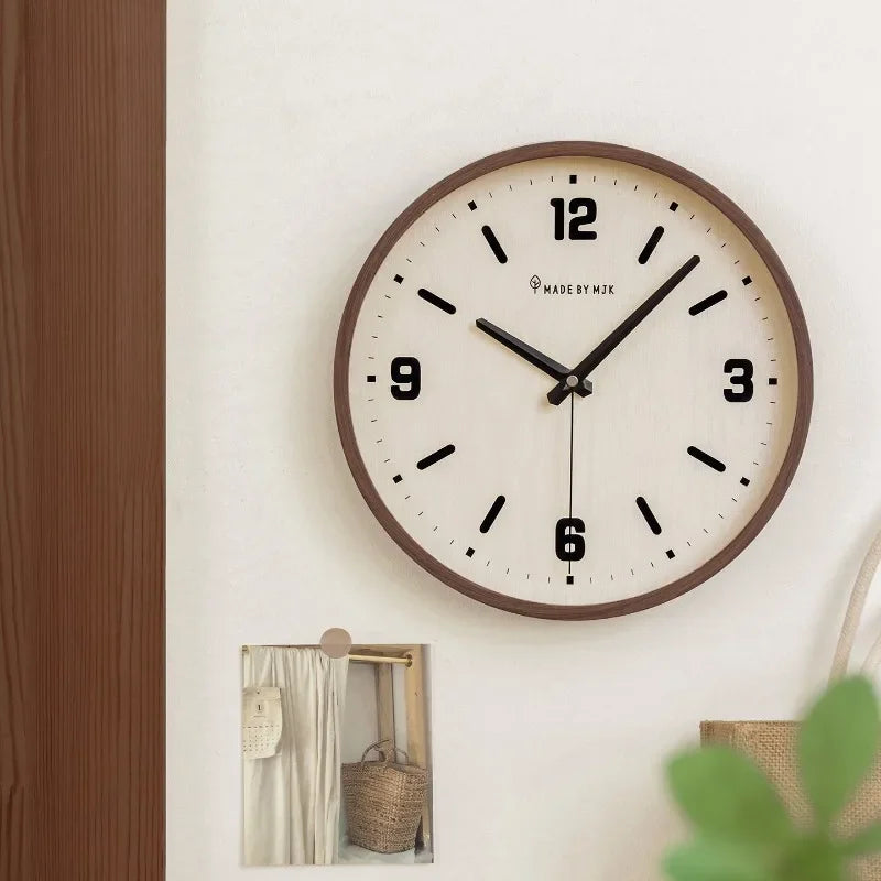 Cream-dial wall clock with a brown rim on a pale wall above a shelf with decorative objects.