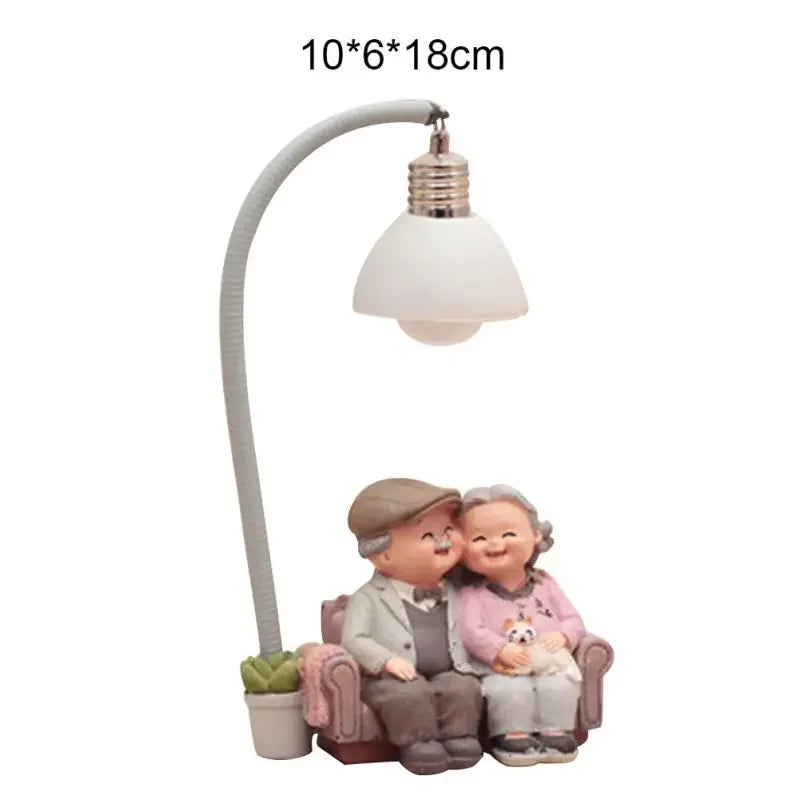 Elderly couple seated on a sofa beneath a curved lamp, with dimensions labelled 10 by 6 by 18 cm