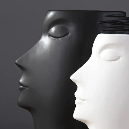 Close-up of black and white face vases showing the sculpted eyelids, noses and lips.