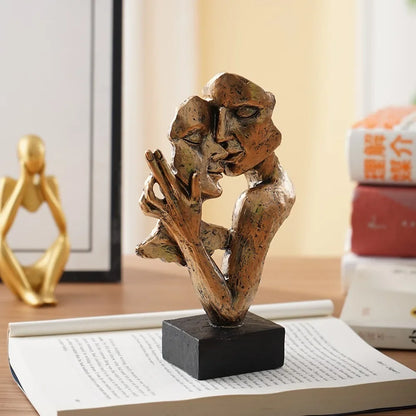 Gold-coloured fragmented couple sculpture with a raised hand, displayed on an open book