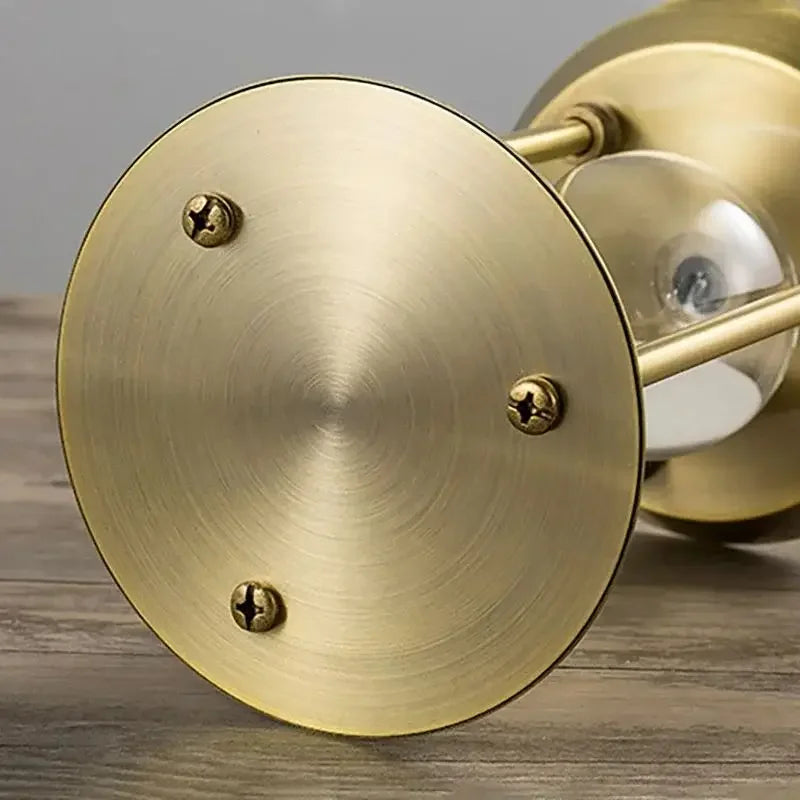 Close-up of the circular gold metal hourglass base showing its brushed finish and three fasteners.