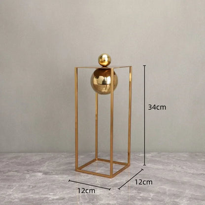 Tall gold-coloured frame and sphere sculpture with a diagram showing 34 cm height and a 12 cm square base