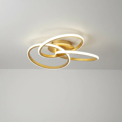 Gold-coloured ceiling light with three intertwined illuminated loops against a white ceiling