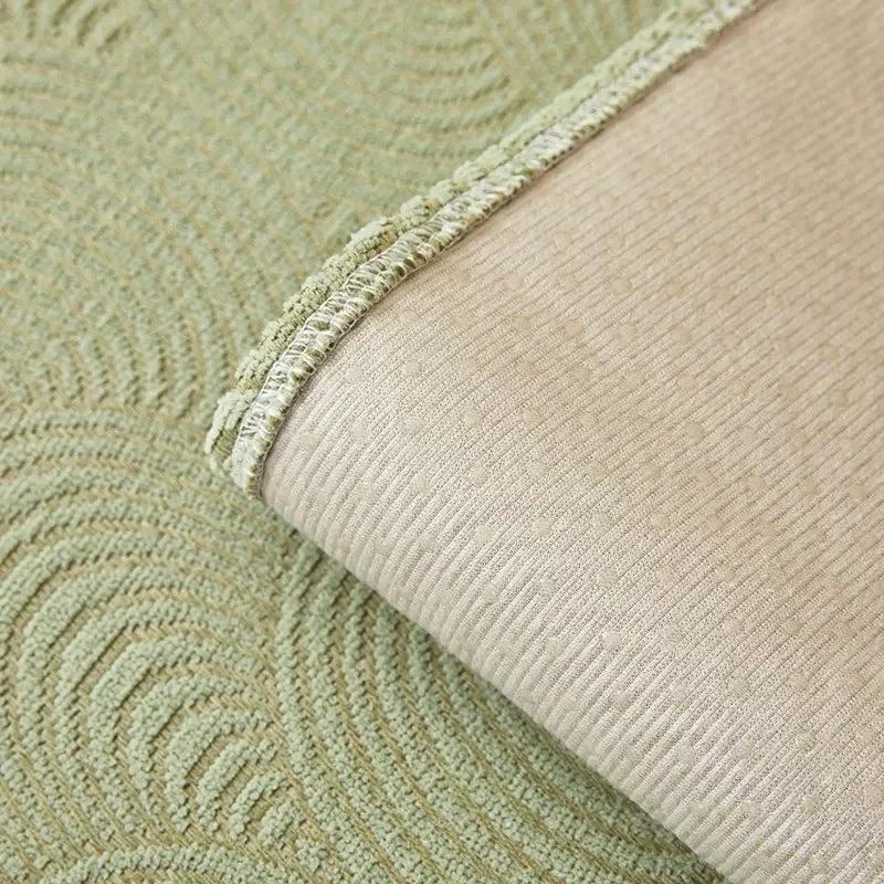 Corner of a green patterned sofa cover turned back to reveal its pale dotted underside.
