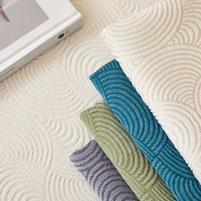 Close-up of cream, blue, green and grey-purple sofa covers showing their raised curved line patterns.