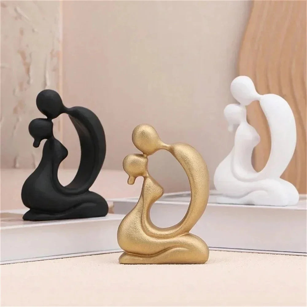 Black, gold-coloured and white abstract kissing couple sculptures arranged on a pale tabletop