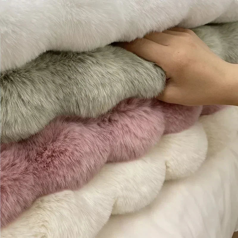Hand between stacked white, green and pink plush rugs, showing their thick textured edges