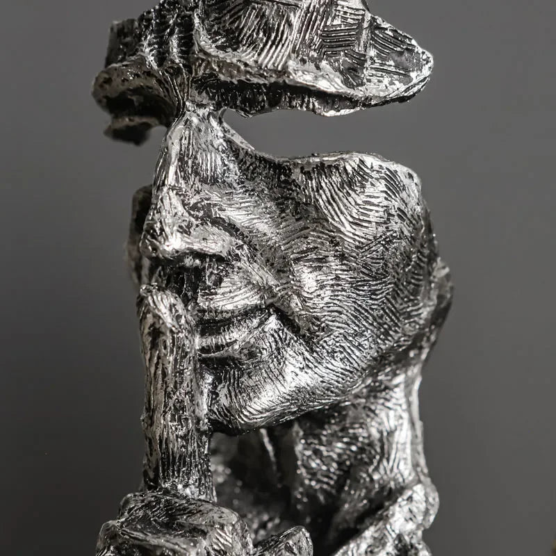 Close-up of a silver-coloured fragmented face sculpture, showing its textured surface and finger at the lips