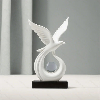 Front view of a white bird sculpture with raised wings and a clear sphere on a black base.