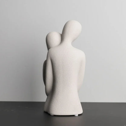 Rear view of a white abstract embracing couple sculpture, showing the taller figure's curved back