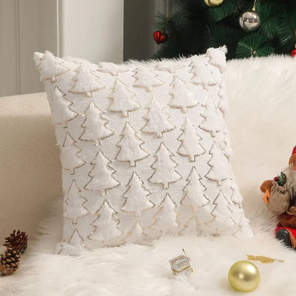 White Christmas cushion cover with raised tree shapes and gold-coloured outlines, displayed on a sofa