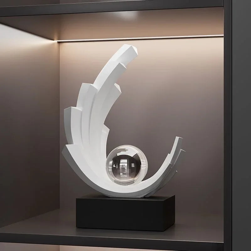 White stepped crescent sculpture with a clear sphere on a black rectangular base on a shelf.