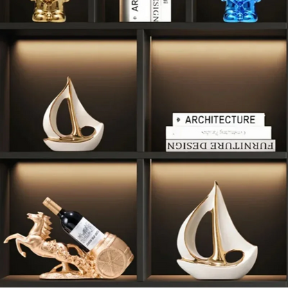 White sailboat sculptures in separate compartments of a dark display cabinet with books and wine holders
