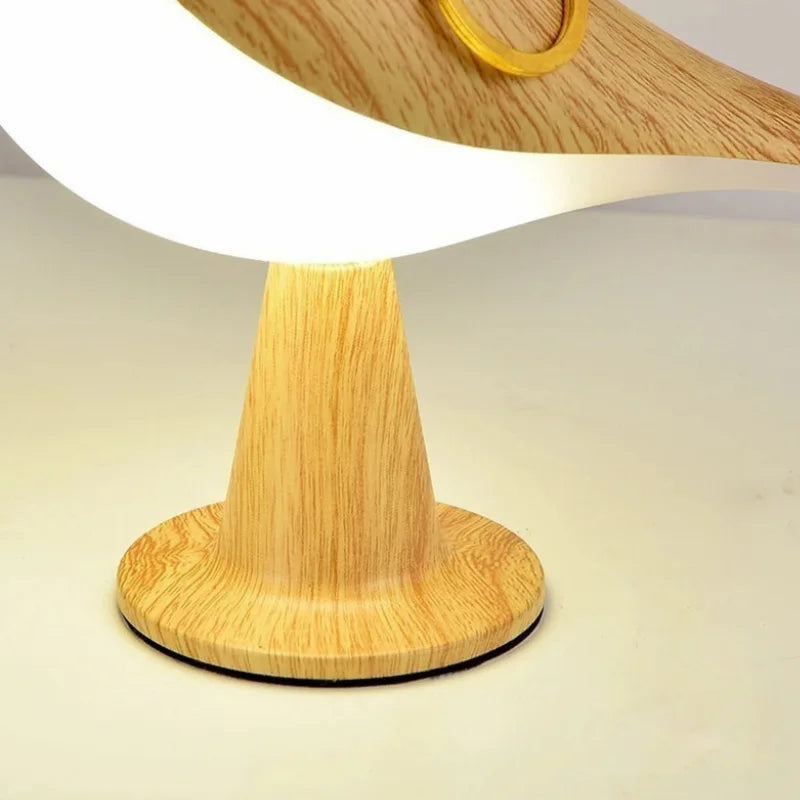 Close-up of a bird-shaped lamp's wood-grain stand, circular base and illuminated white body
