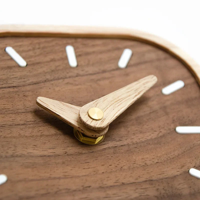 Close-up of a wooden clock's pale hands, gold-coloured central pin and white hour markers