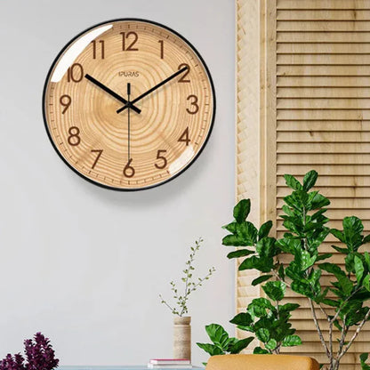 Wood-ring dial wall clock with black hands on a white wall beside wooden blinds.